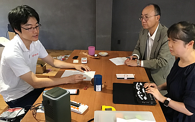 インタビュー風景。左側が山蔦代表。机を挟んで右側にITステーション職員（幸田、他１名）が対面しています。