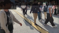 広場にできた長い行列沿いに歩く画像