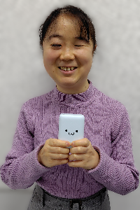 モバイルバッテリーを持つ幸田 写真:しろちゃんのついたモバイルバッテリーを持って微笑む幸田。