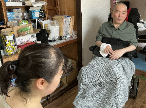 写真：別角度から撮影したインタビュー風景。左手前の幸田（後ろ姿）に対面する熱心に語る黒澤さん