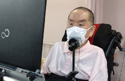 写真：職場にてマスクを着用してミレットでパソコンを操作する黒澤さん