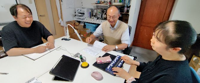 インタビューの様子 写真:アクセスエール社にてインタビューしている様子。テーブルをはさんで左が松尾光晴社長、対面する形で後姿の幸田。その間側面に同行職員。